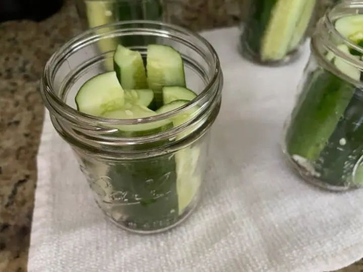 packing cucumber spears in mason pint size jars to be canned.