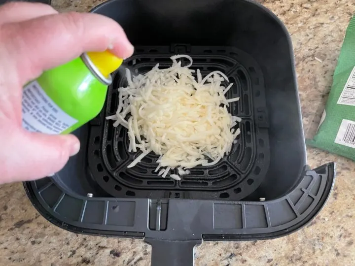 putting cooking spray on shredded hash browns before cooking in the air fryer.