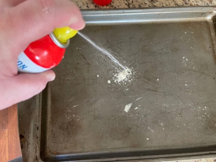 greasing a cookie sheet before adding biscuit dough.