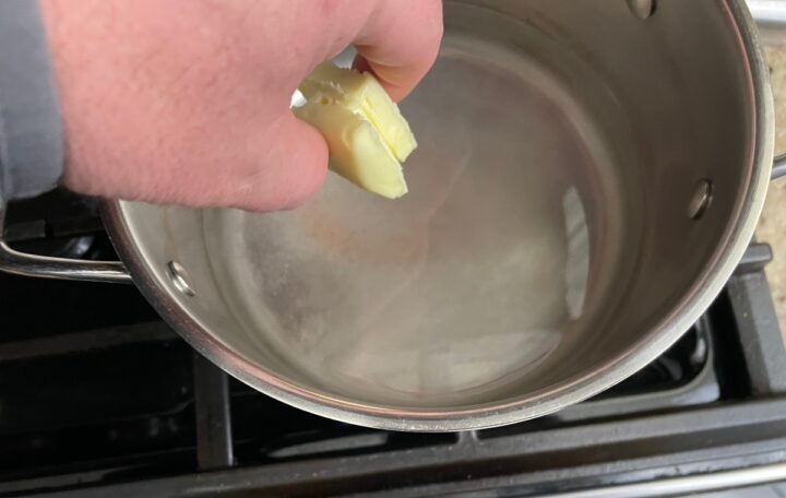 adding butter to a stock pot.