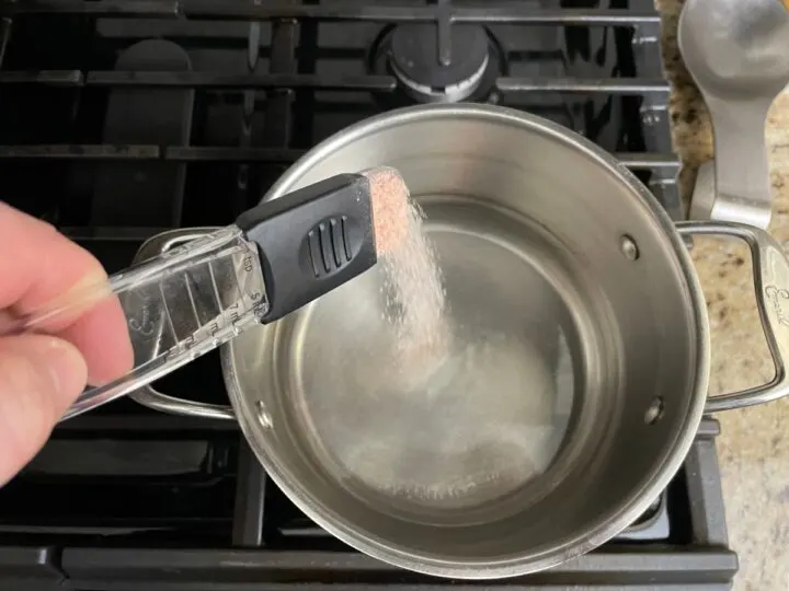 adding salt to a stock pot.