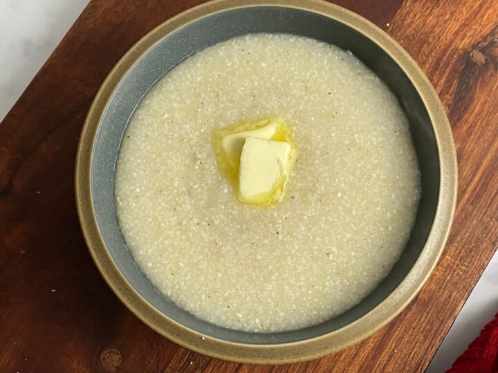 Closeup of cooked grits in a bowl with butter on top.