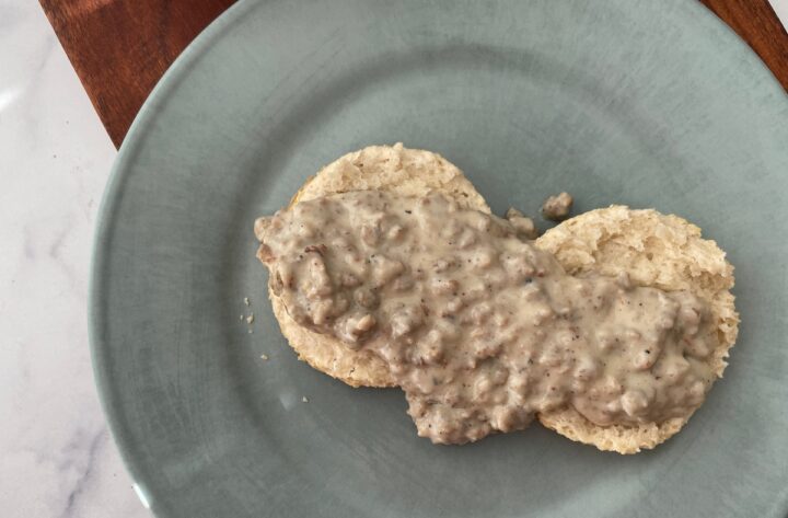 Plated sausage gravy on a homemade biscuit overhead shot.
