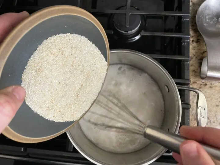 adding grits to a stock pot while whisking.