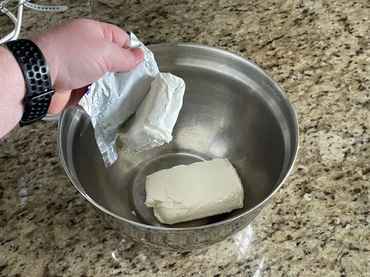 adding cream cheese to a bowl.
