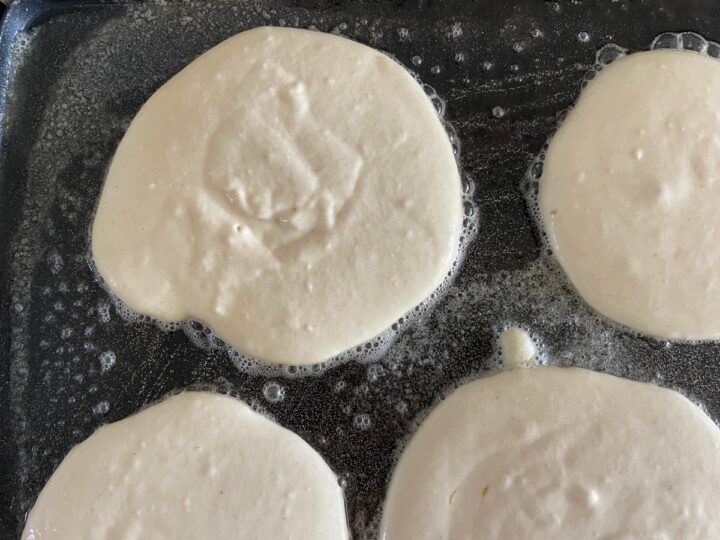 pancakes cooking on a griddle.