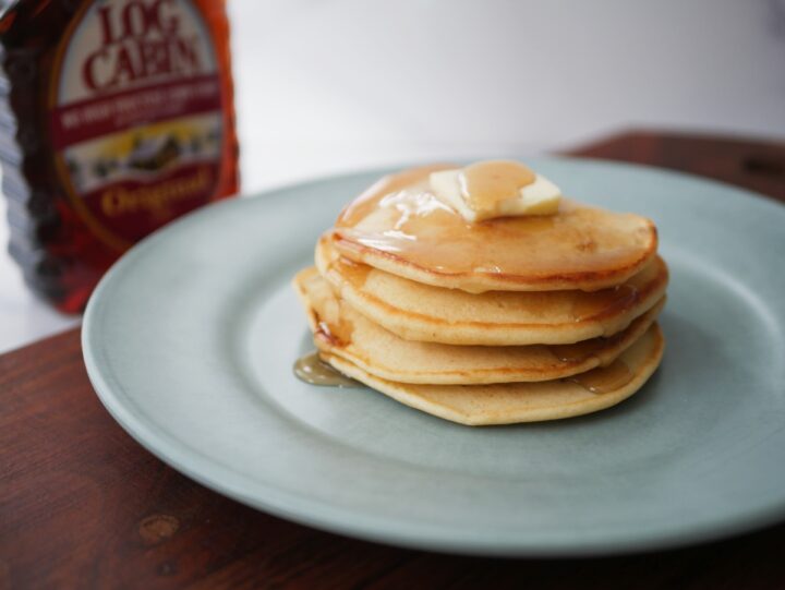 Stack of old fashioned pancakes with syrup and butter on top.
