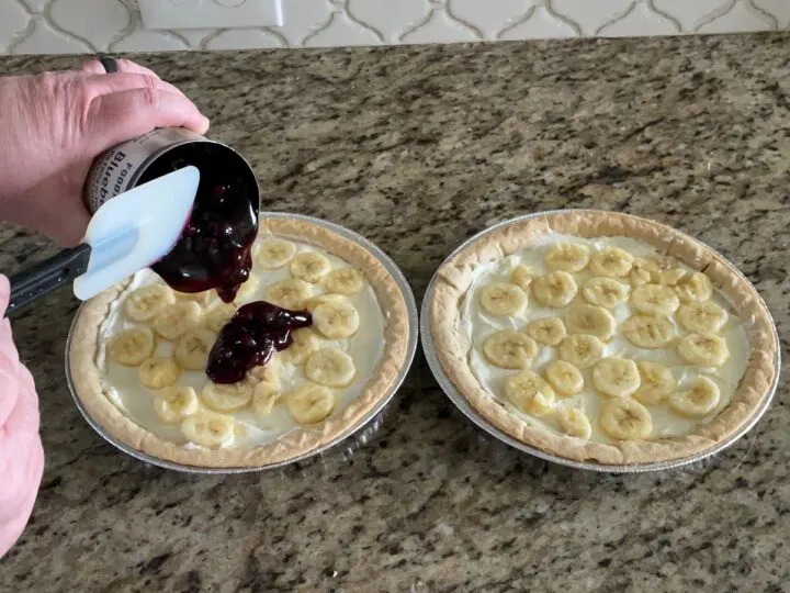 Adding blueberry pie filling to blueberry cream cheese pie.