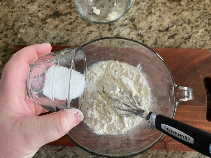 adding sugar to a mixing bowl.