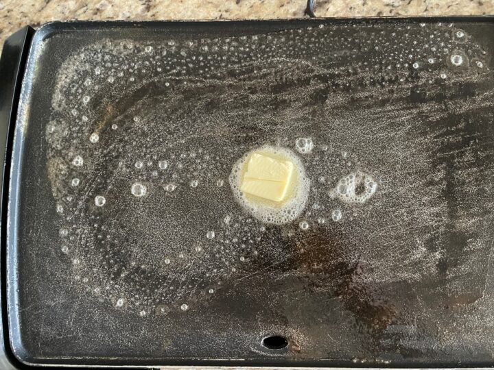 showing melted butter on a electric griddle for cooking pancakes on.