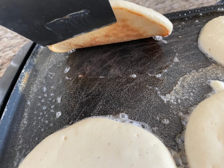 checking to see if the under side of a pancake is ready to be flipped on the griddle.
