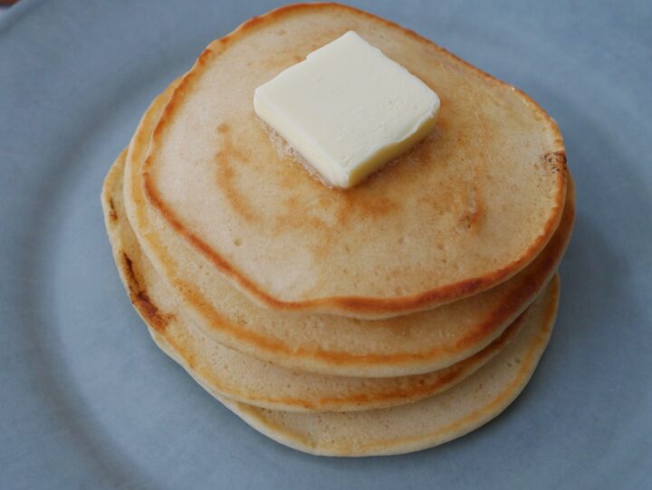 90 degree view of a stack of old fashioned pancakes with butter on top.