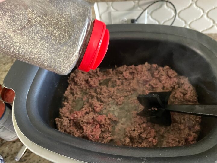 adding black pepper to ground meat.