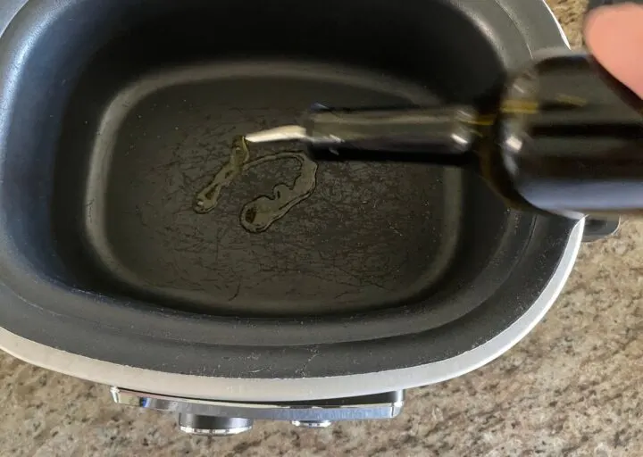 Adding oil to slow cooker for a recipe.