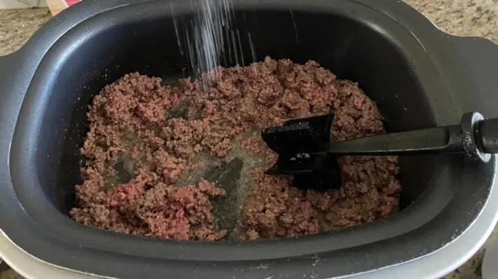 adding salt into ground meat while cooking in the slow cooker on stove top function.