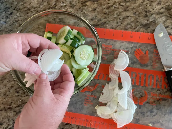 adding onions to the cucumbers in a medium size bowl.