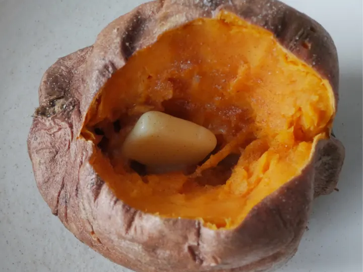 Closeup picture of a baked sweet potato with butter and cinnamon sugar.