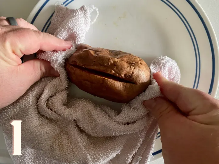 Using a tea towel to push the ends to open up the middle of the baked sweet potato first photo.