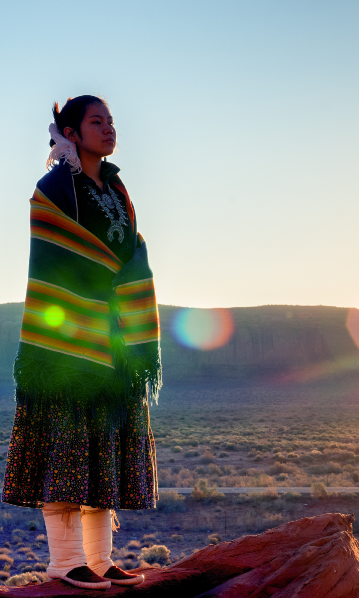 Native American Lady standing out on the reservation looking across the vast dessert at sunset. 