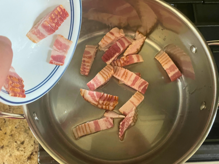 Adding bacon into a stock pot to render out the fat.