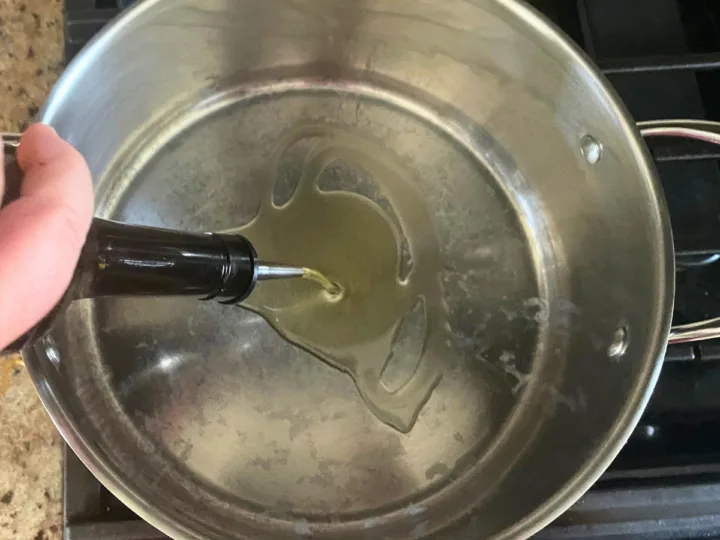 Adding olive oil to a stock pot.