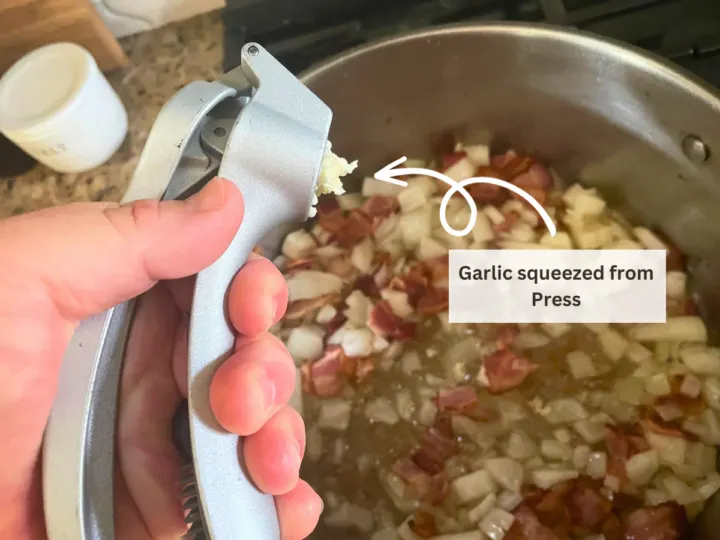 Once garlic is in the press, squeeze the handle to push the garlic out the other side. This leaves the skin behind.