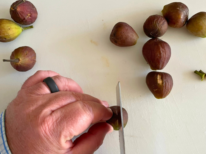 This is a picture of me using a sharp knife to cut the figs in half in order to prepare the figs to dehydrate. 