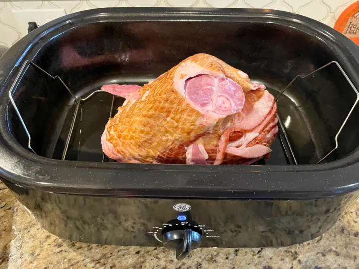 This image shows a smoked ham sitting in a roaster oven ready to be reheated.
