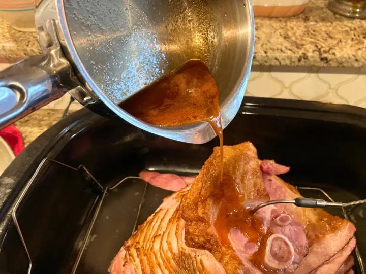 This pictures shows pouring a glaze over a smoked ham that has been reheated.