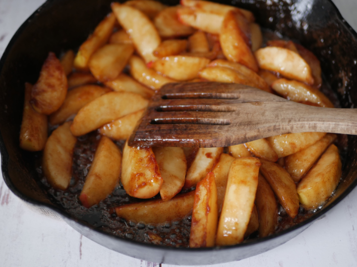 This image shows how to stir the apples in a cast iron skillet to keep them from burning.