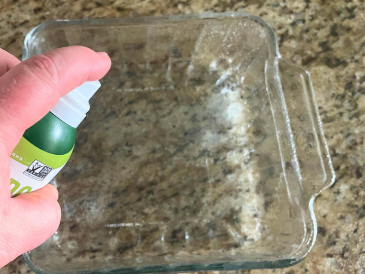 This is a image of a person using avocado spray to coat a baking dish. 