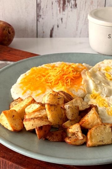 Crispy air fryer red potatoes served with eggs bacon and cheese grits
