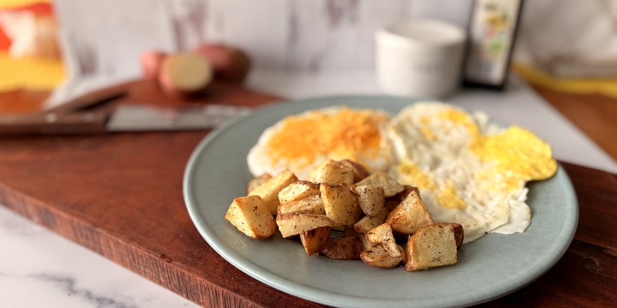 Air fryer breakfast potatoes served with eggs bacon and grits
