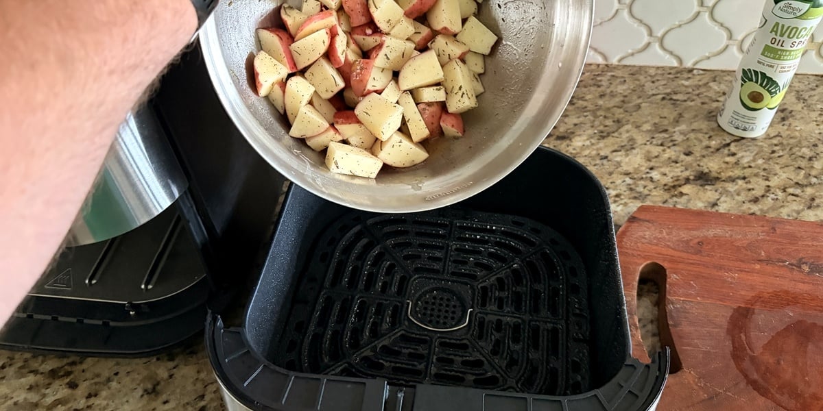 Seasoned diced red potatoes inside air fryer basket