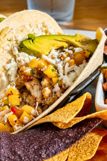 Blackened fish tacos topped with mango salsa, avocado, and queso fresco served with tortilla chips and black bean salad at Rusty Hooks Dockside Grill in Southport, NC.