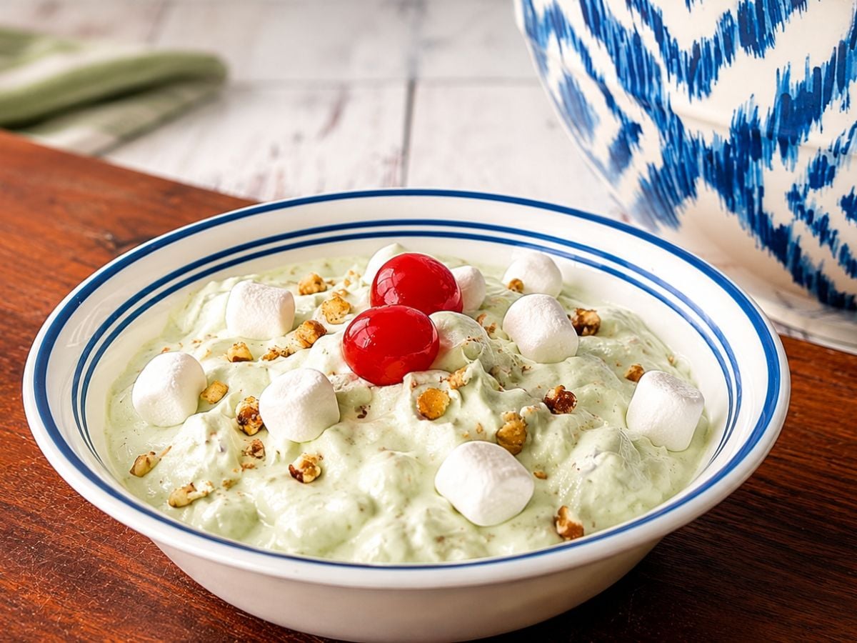 A bowl of old fashioned Watergate Salad topped with maraschino cherries, mini marshmallows, and chopped pecans.