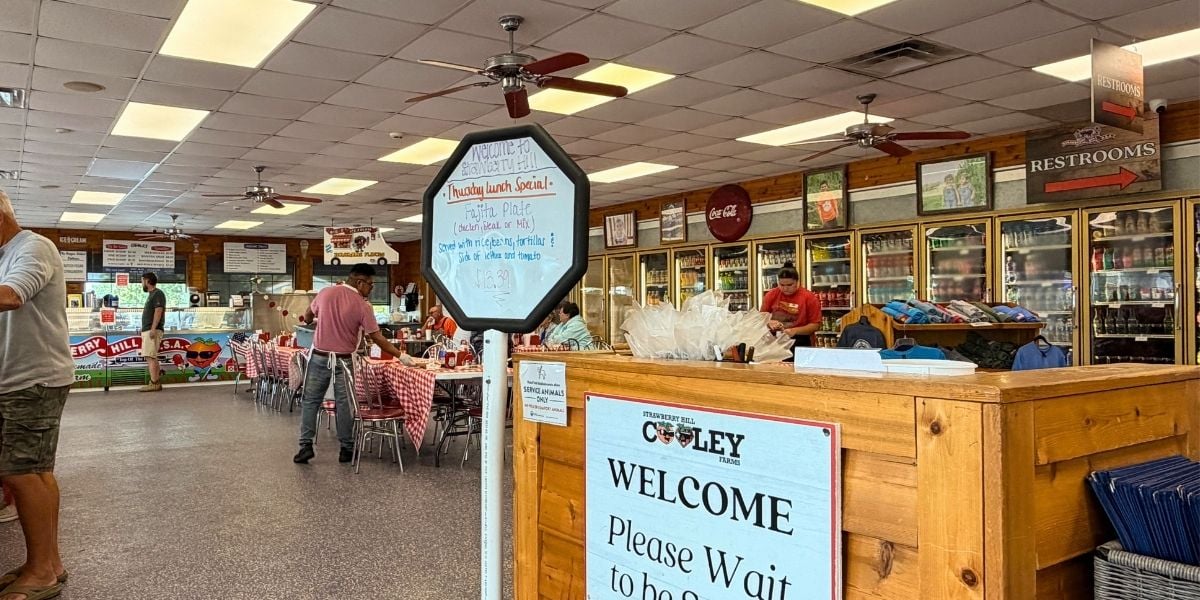 The indoor dining area and wooden welcome counter featuring a handwritten lunch specials sign at Strawberry Hill USA Cafe in Chesnee, South Carolina.