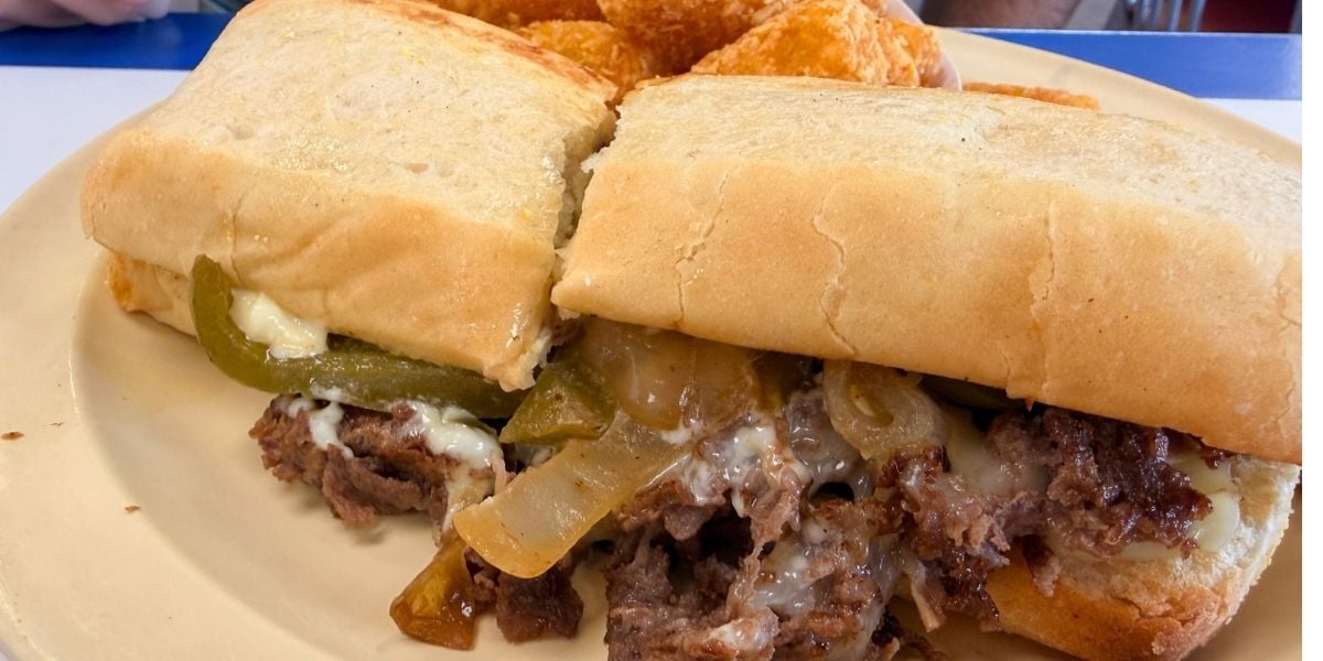A grilled Philly cheesesteak sandwich with shaved beef, melted cheese, peppers, and onions on a hoagie roll at Strawberry Hill USA Cafe in Chesnee, South Carolina.