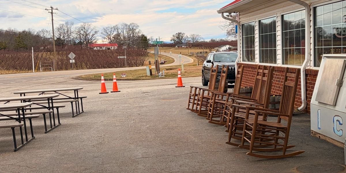 Wooden rocking chairs and outdoor picnic tables lined up on the patio at Strawberry Hill USA Cafe in Chesnee, South Carolina.