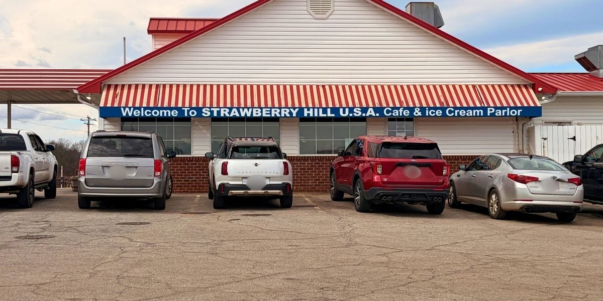 The side exterior building of Strawberry Hill U.S.A. Cafe and Ice Cream Parlor showing a blue welcome sign above the parking lot in Chesnee, South Carolina.